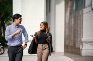 Portrait of two colleagues walking. They are both smiling as they chat.